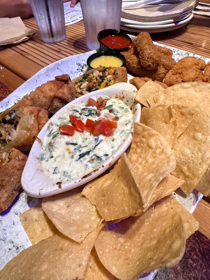 Mesa de aperitivos com nachos, dip e frango empanado